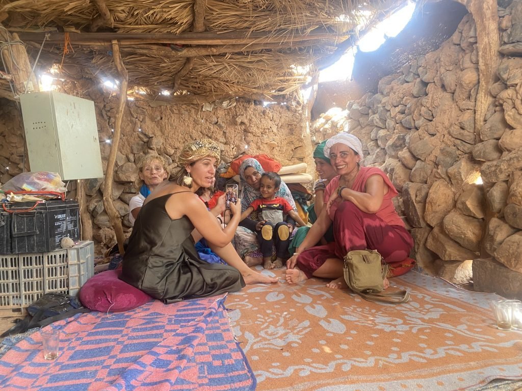 Guests and hosts sitting together on rugs inside a nomad tent