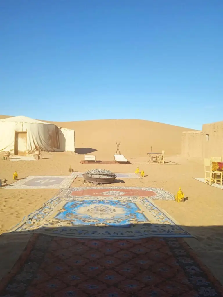 A tent set up on carpets among the dunes of the Private Camp